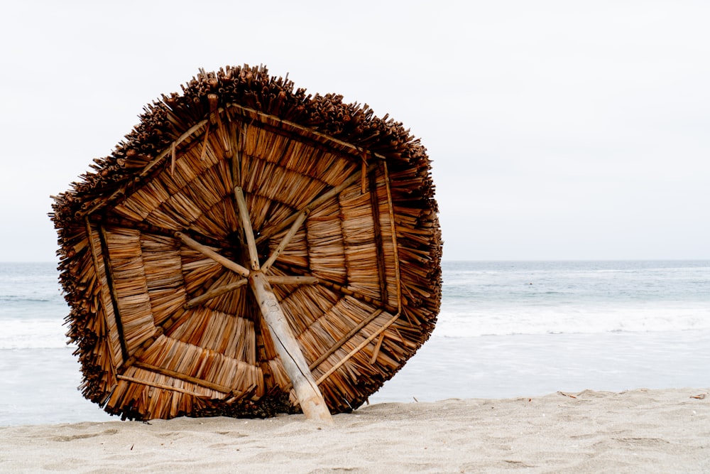 a straw umbrella sitting on top of a sandy beach