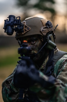 a man in camouflage holding a gun and wearing a helmet