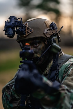 a man in camouflage holding a gun and wearing a helmet