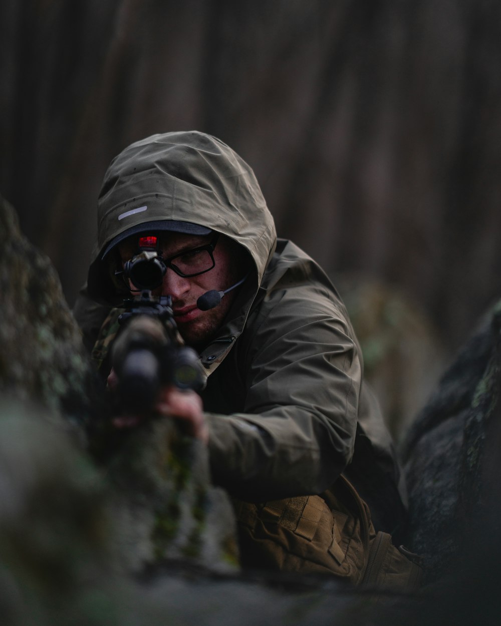 a man in a hooded jacket aiming a rifle