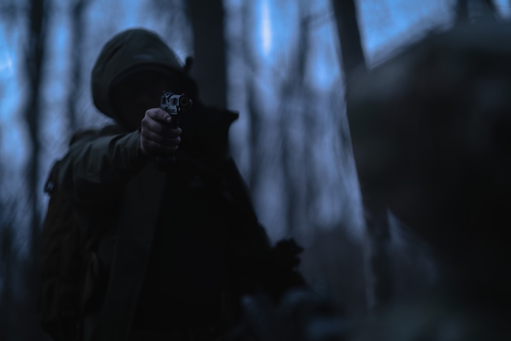 a person holding a gun in a dark forest