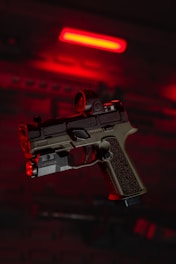 a close up of a gun with a red light in the background
