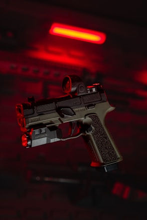 a close up of a gun with a red light in the background