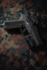 a close up of a gun on a camouflage background