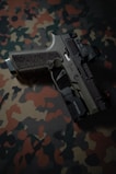 a close up of a gun on a camouflage background