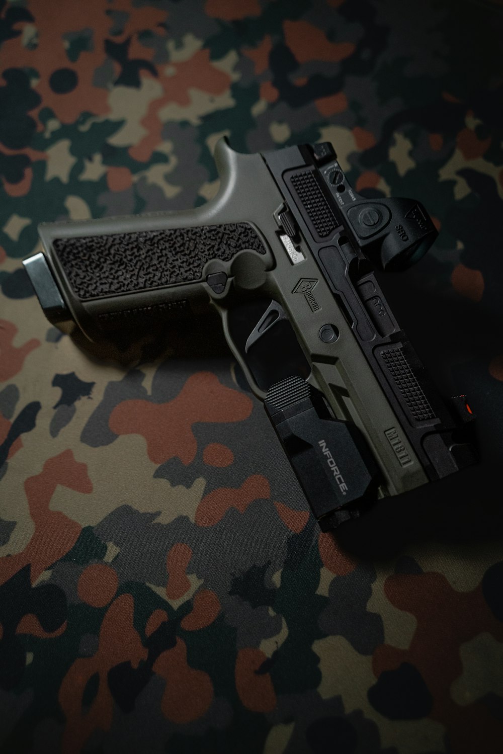 a close up of a gun on a camouflage background
