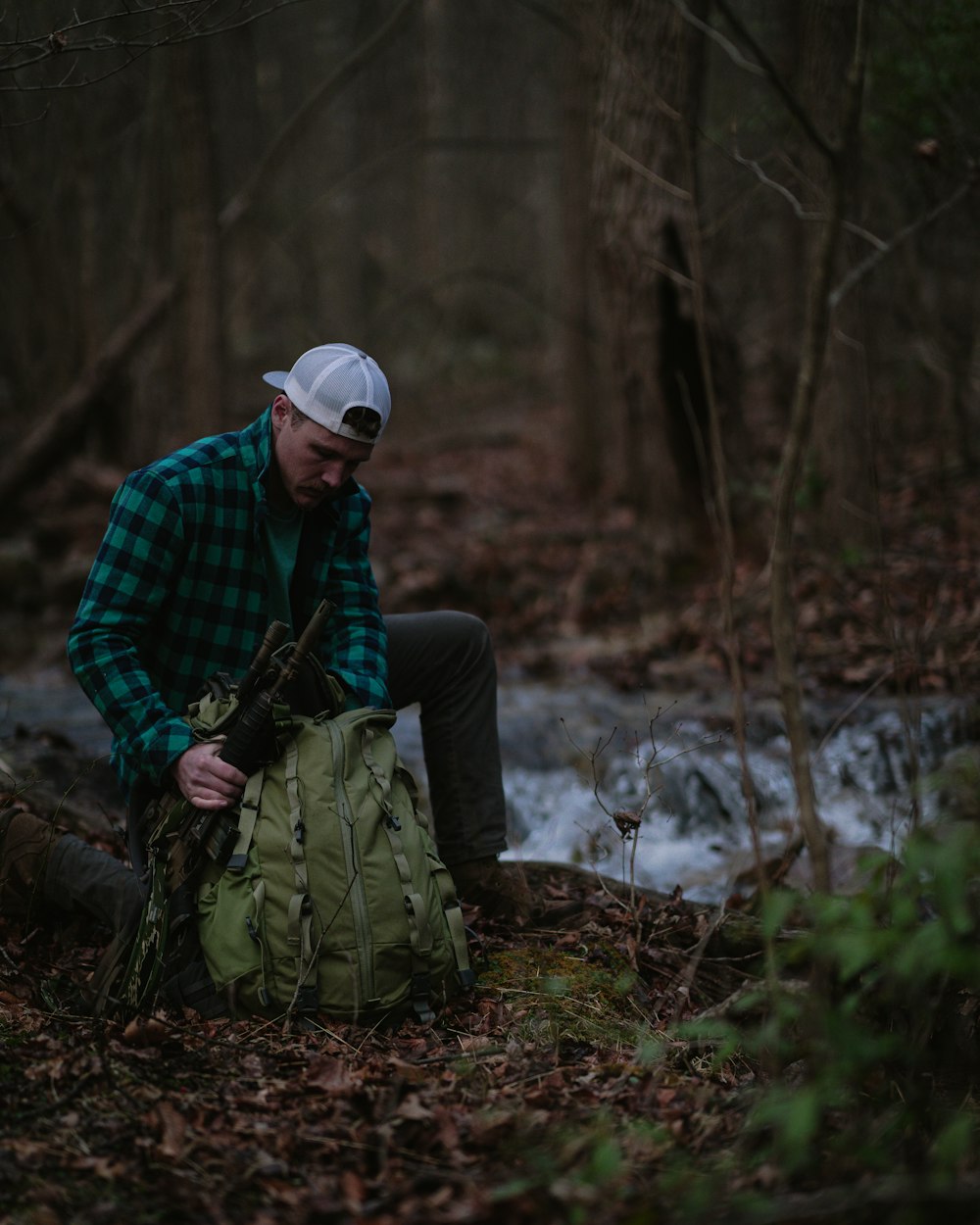 a man sitting on the ground in the woods