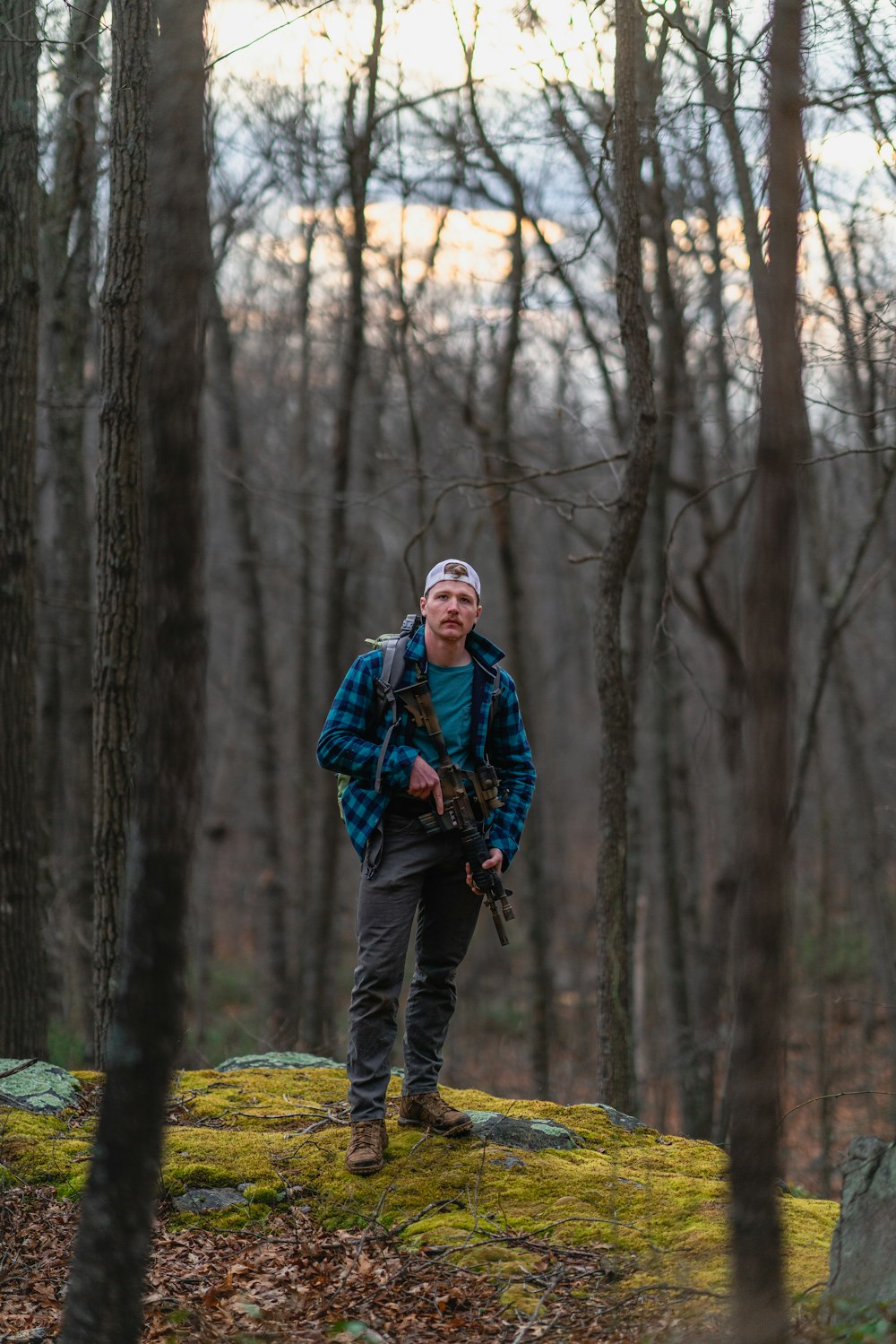 a man standing on a moss covered rock in the woods