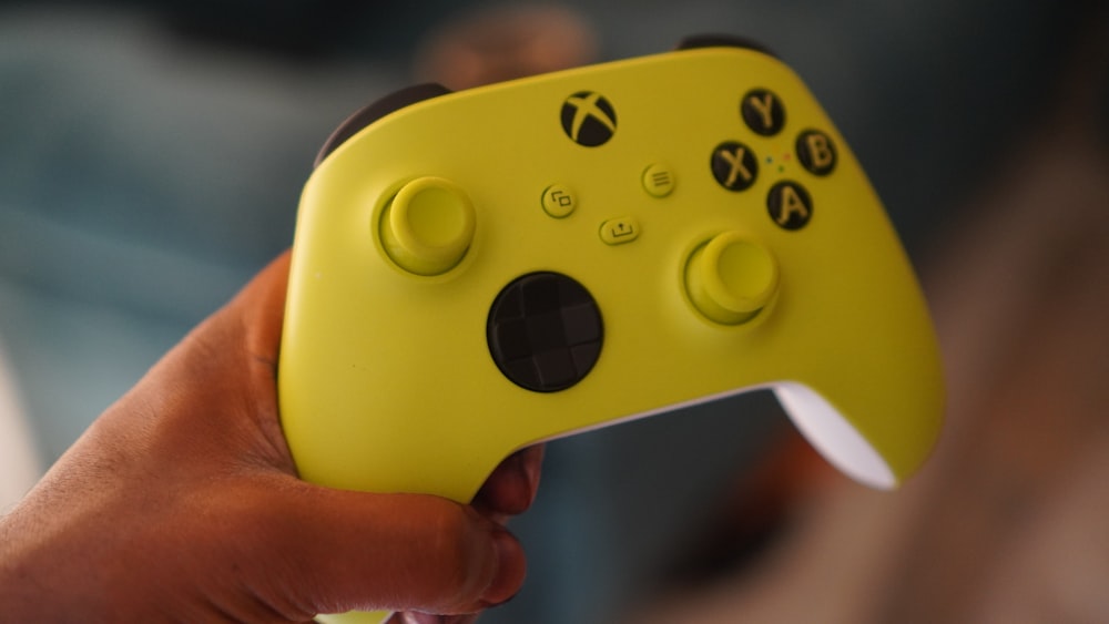a close up of a person holding a yellow controller