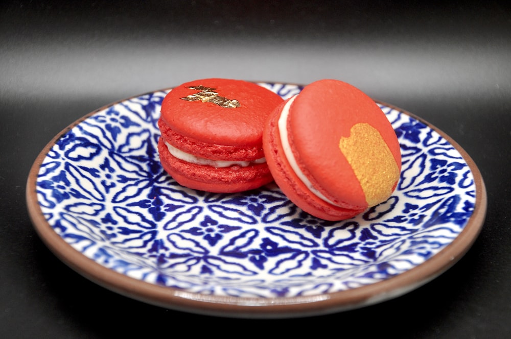 two red macaroons on a blue and white plate
