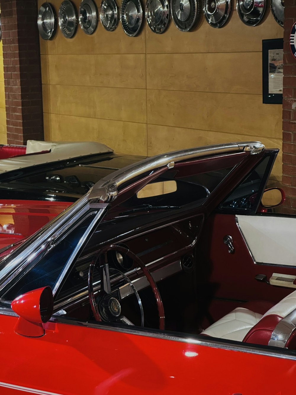 um carro vermelho estacionado em uma garagem ao lado de outros carros