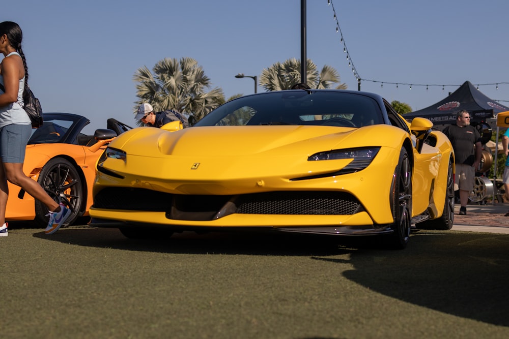 a woman standing next to a yellow sports car