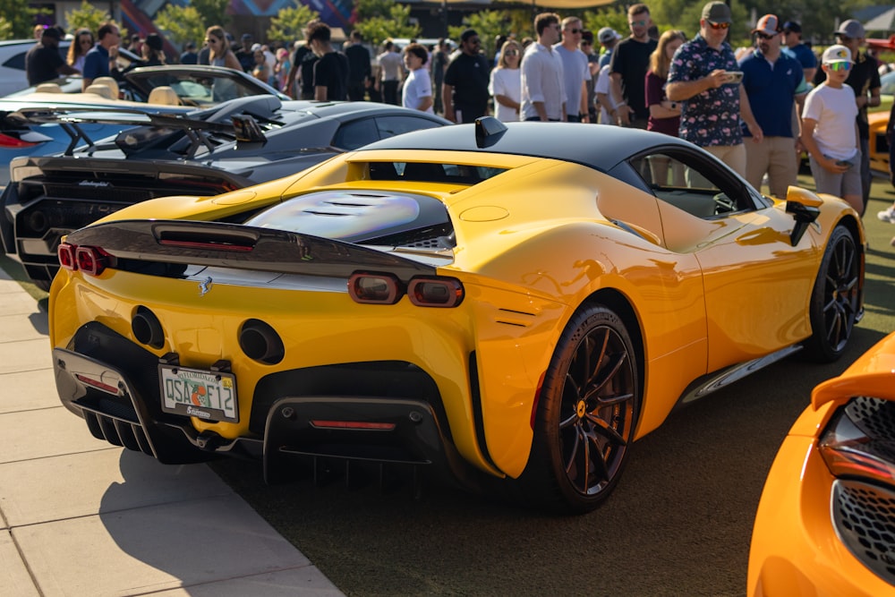 a yellow sports car parked in front of a crowd of people