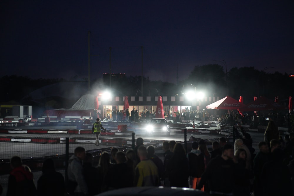 a crowd of people standing around a parking lot at night