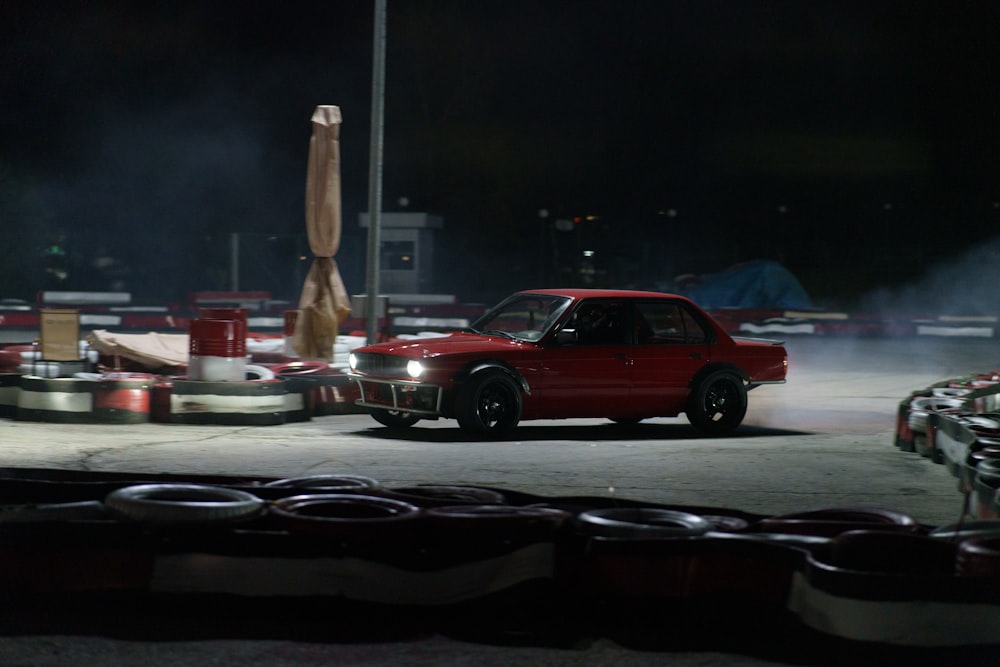 a red car parked in a parking lot at night