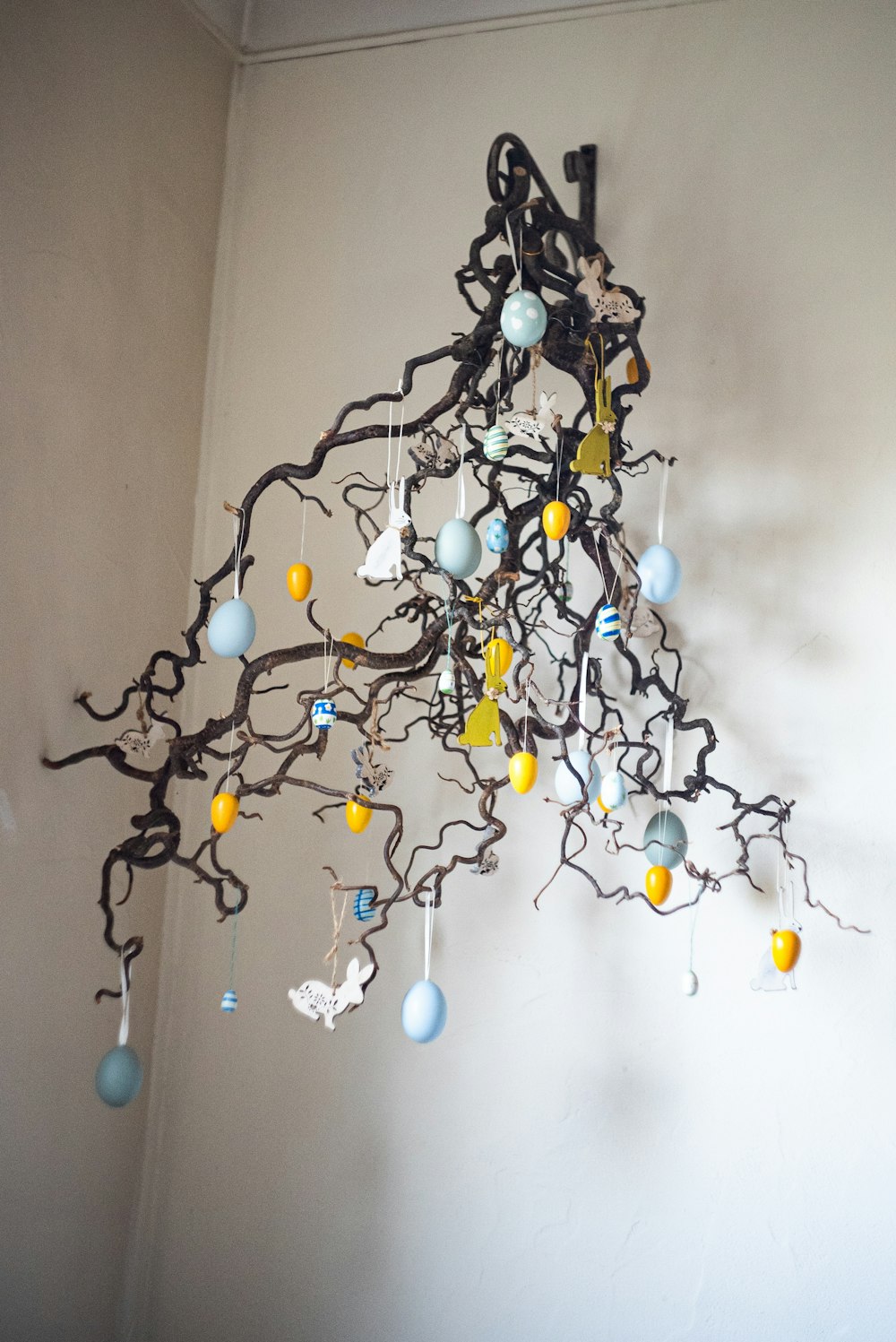 a sculpture made of branches and eggs hanging from a wall