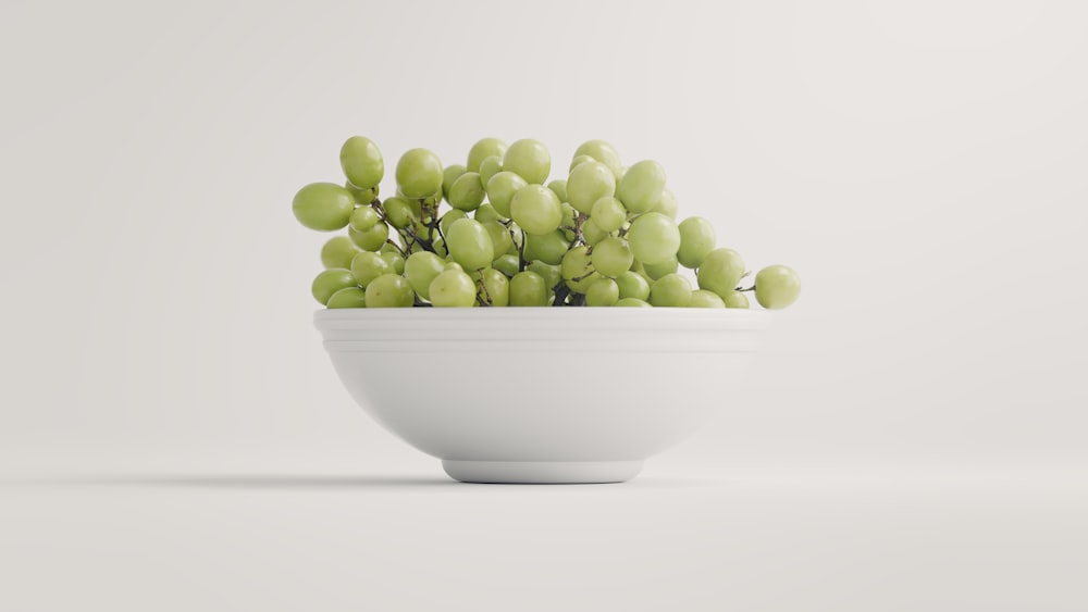 a white bowl filled with green grapes on top of a table