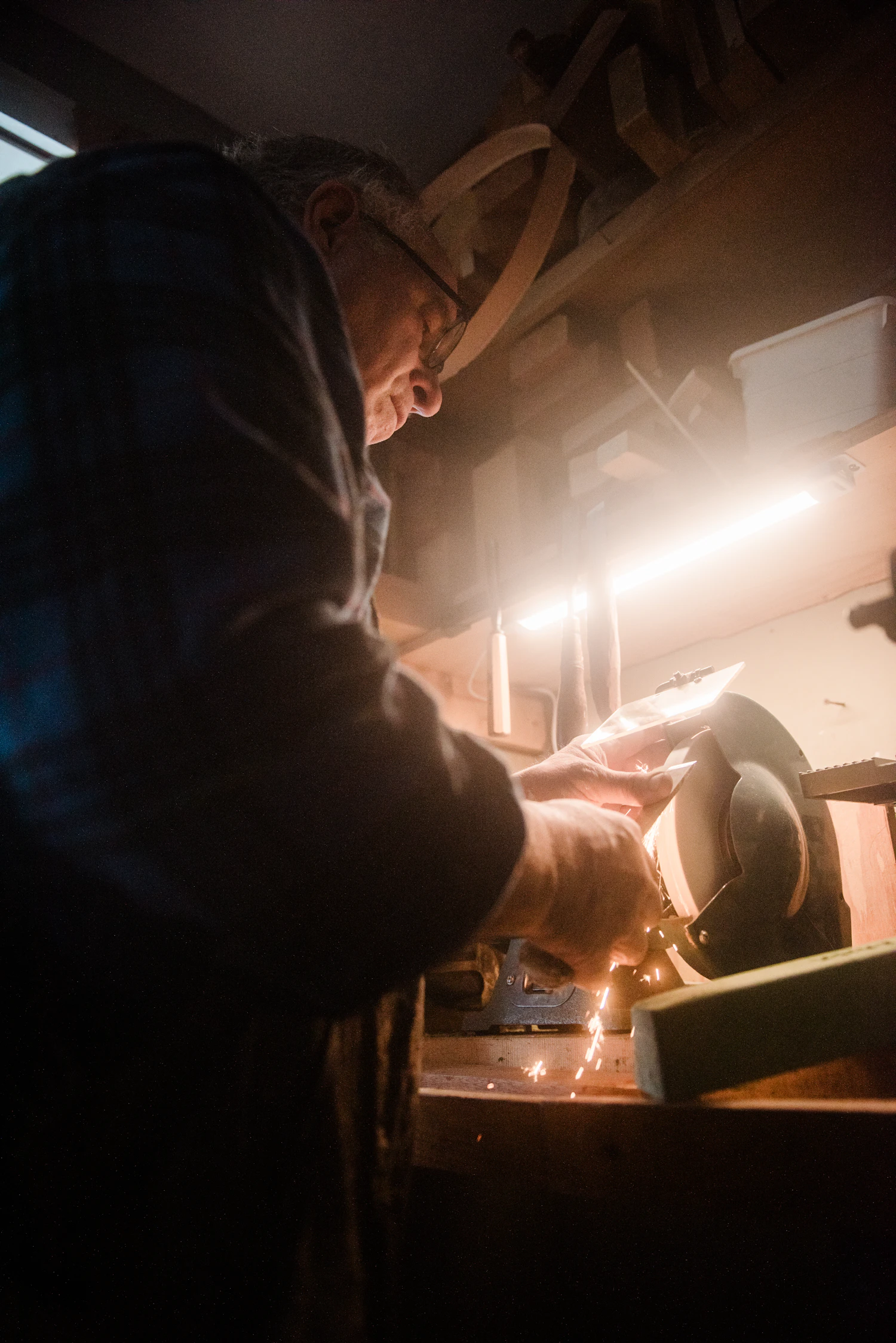 Sparks flying from a grinder at a dim workbench, the only strong light in the room