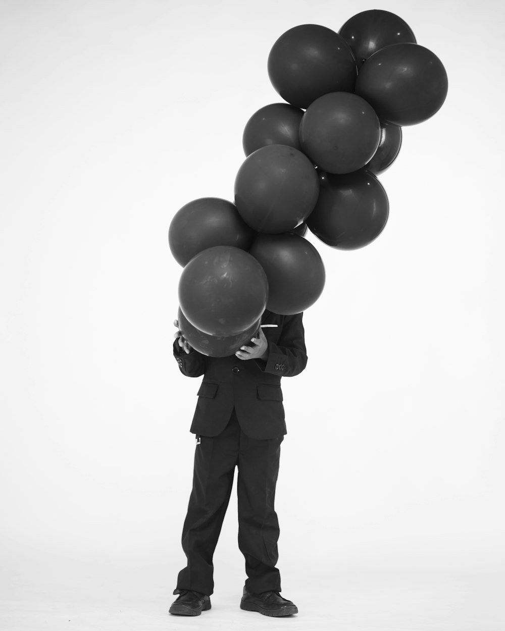 a man in a suit holding a bunch of balloons