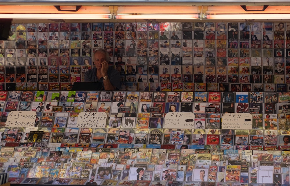 a man sitting in front of a wall covered in pictures