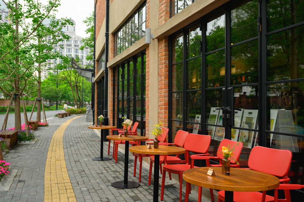 a sidewalk lined with tables and chairs next to a building