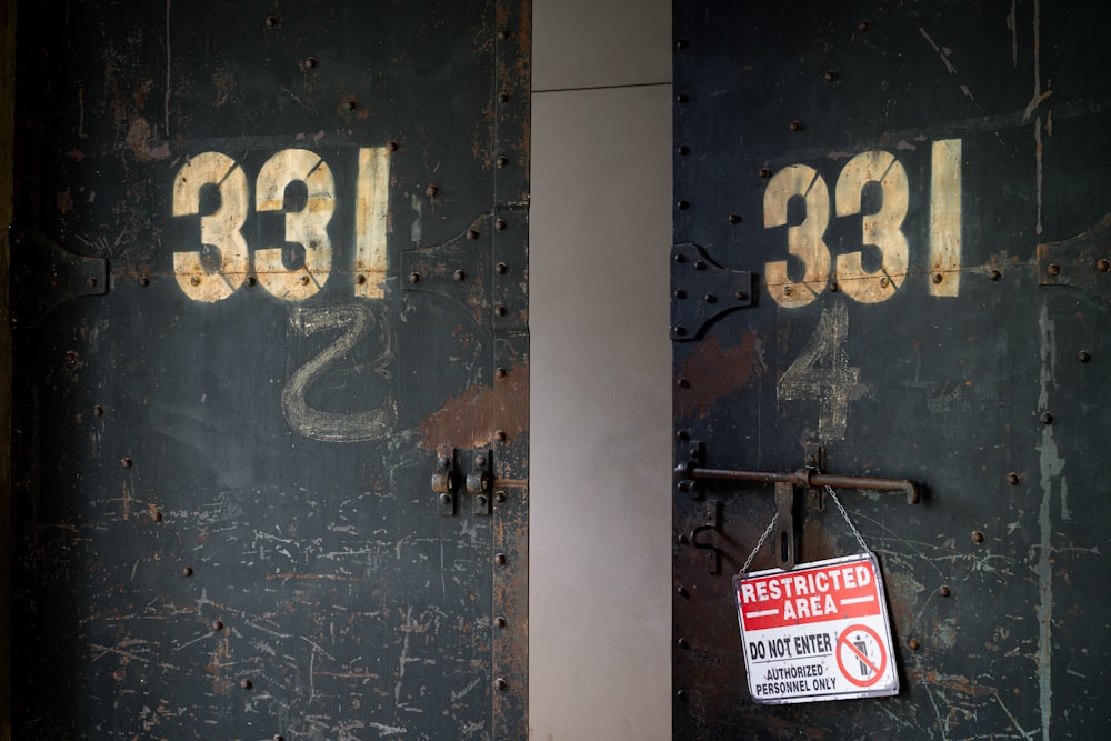 a rusted metal door with a sign hanging on it