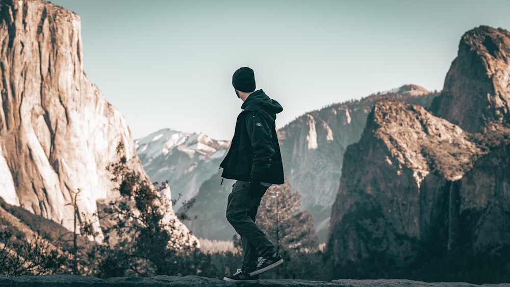 a man standing on top of a mountain next to a forest