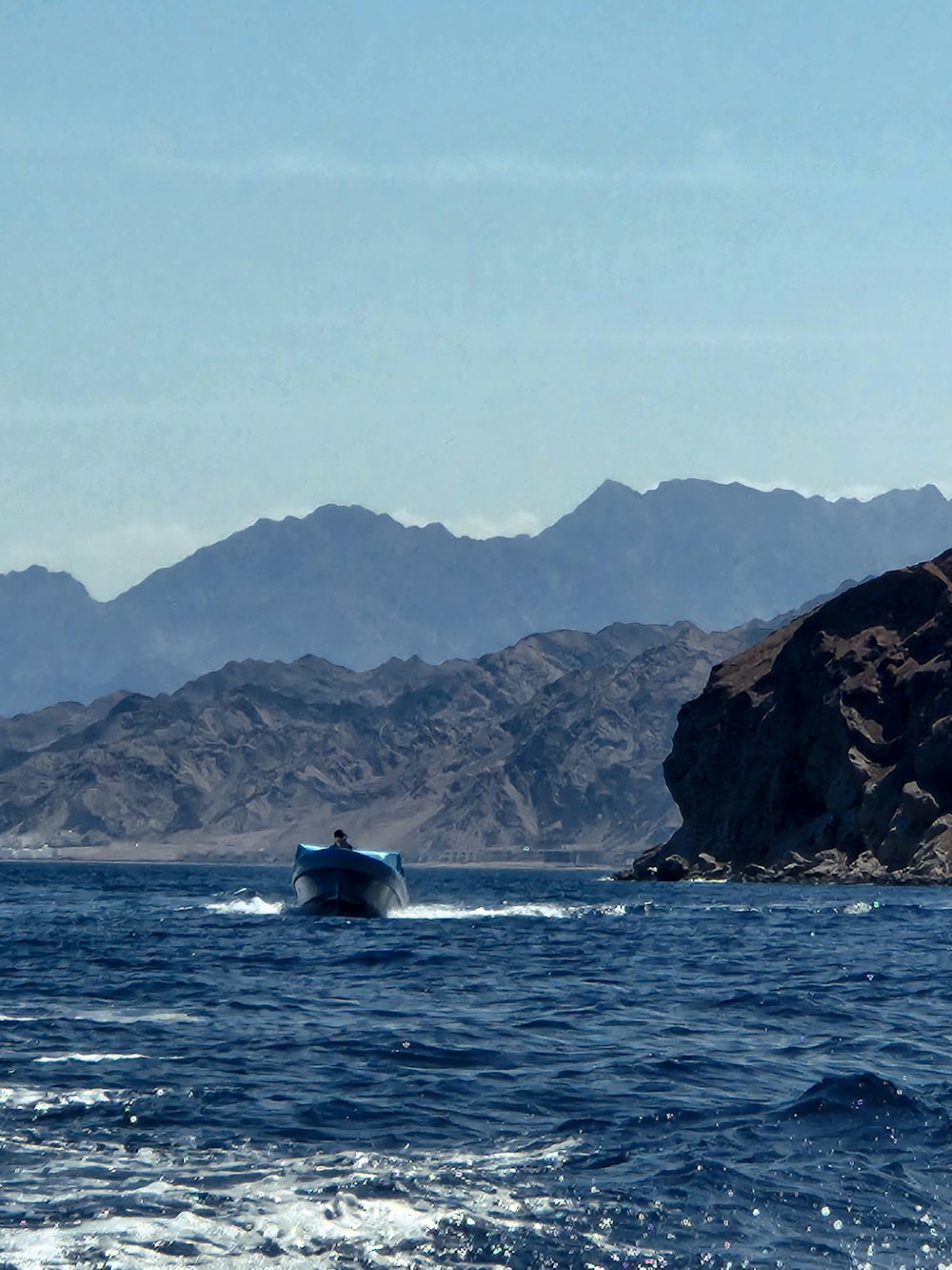 a boat in the middle of a body of water with mountains in the background