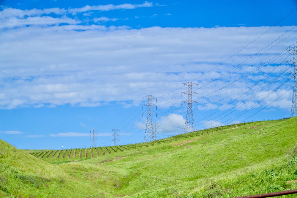 a grassy hill with power lines in the background