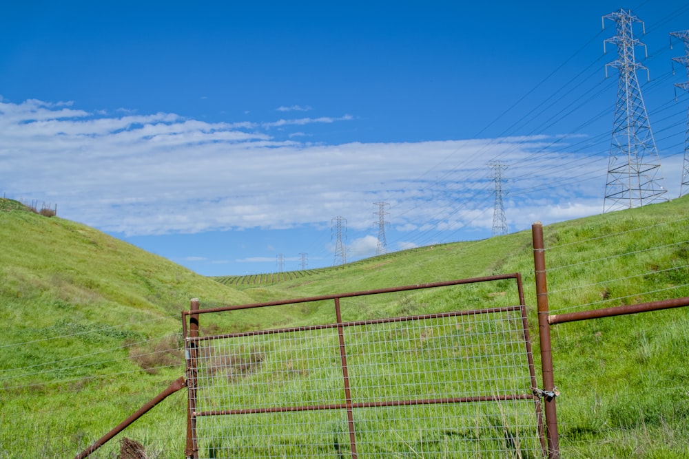 a fenced in area with a grassy hill in the background