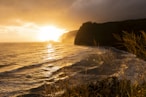 the sun is setting over the ocean on a cloudy day