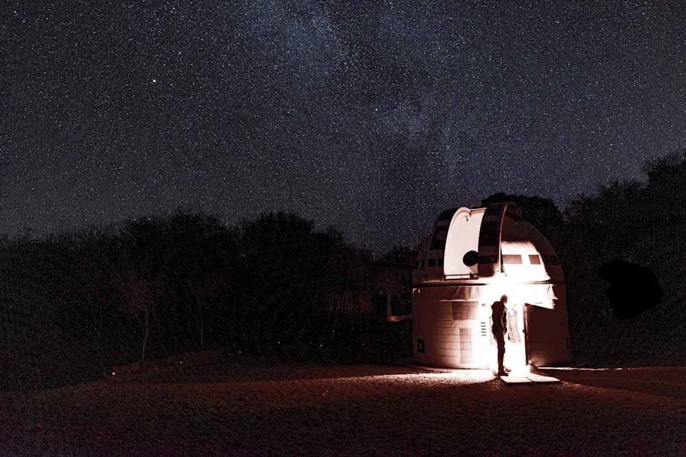 a man standing in front of a telescope at night