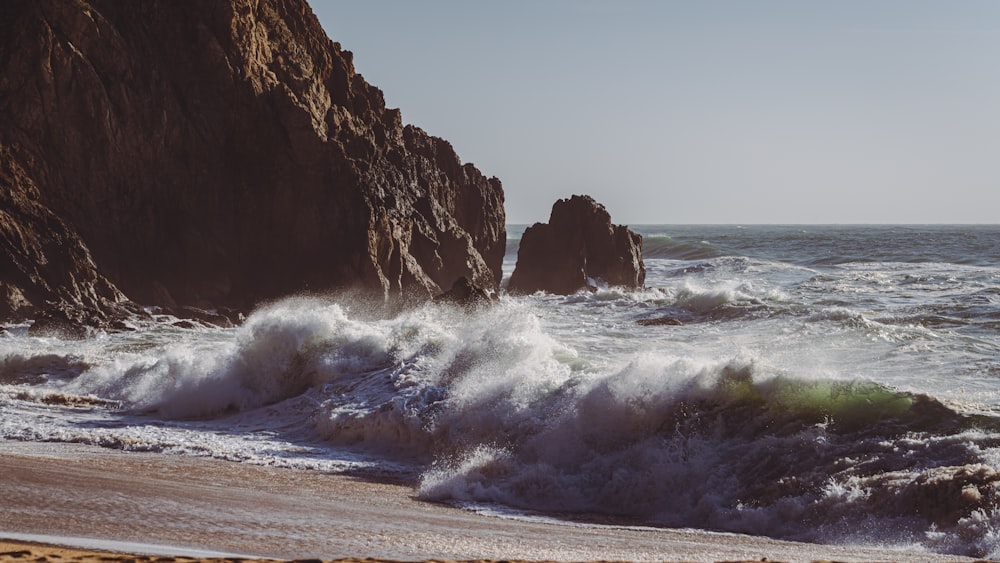 a beach with waves crashing against the rocks