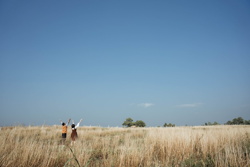 two people standing in a field flying a kite