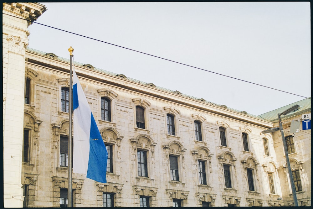 a blue and white flag on a pole in front of a building