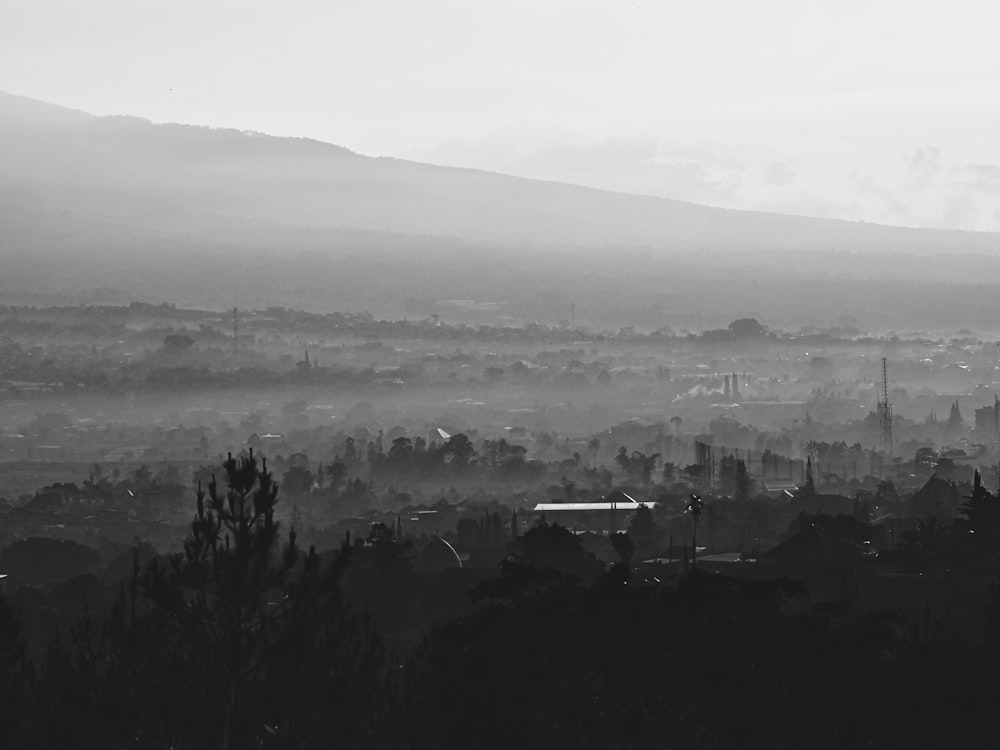 a black and white photo of a foggy city