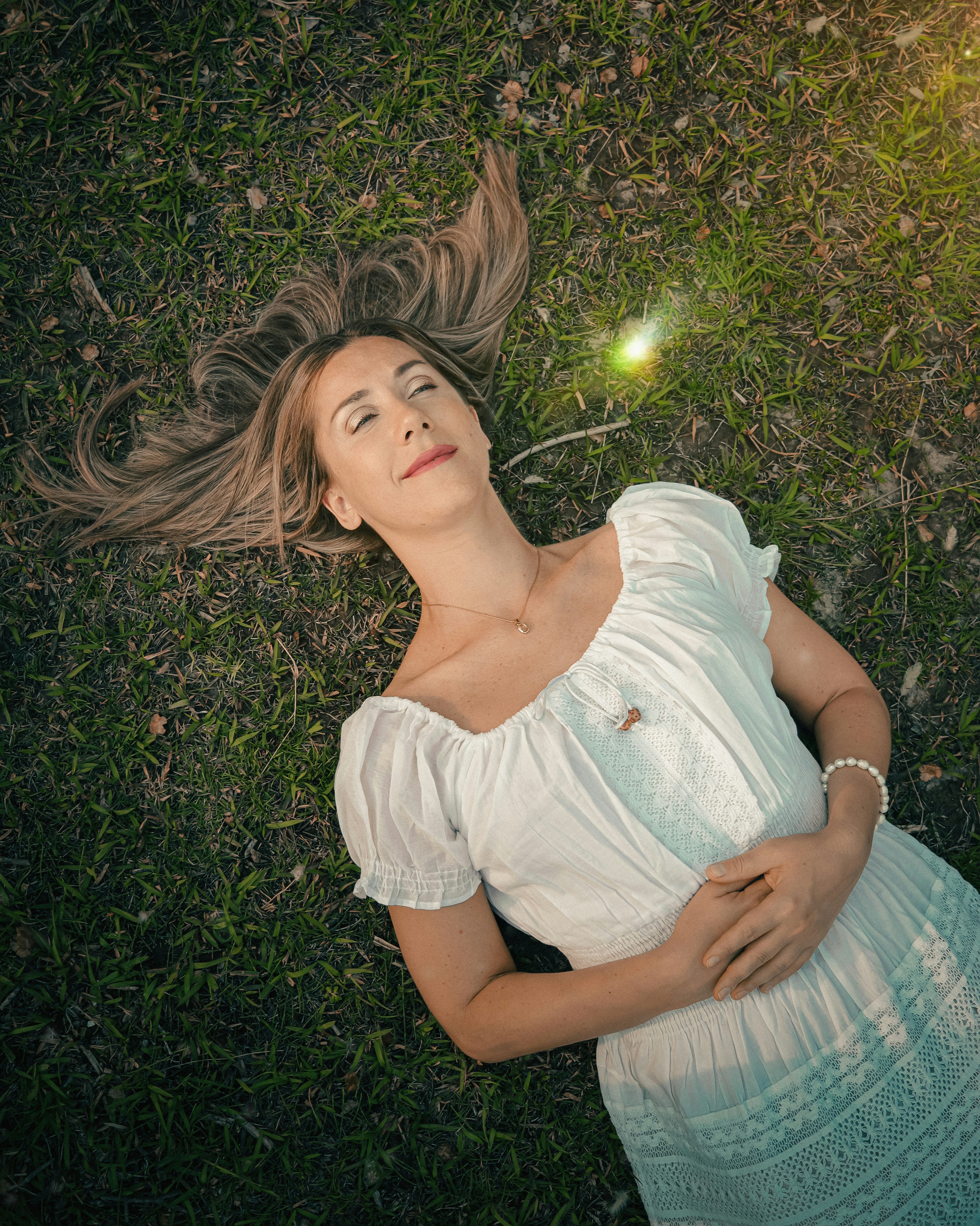 a woman laying in the grass with her hair blowing in the wind