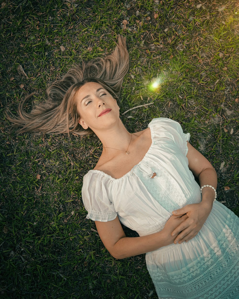 a woman laying in the grass with her hair blowing in the wind