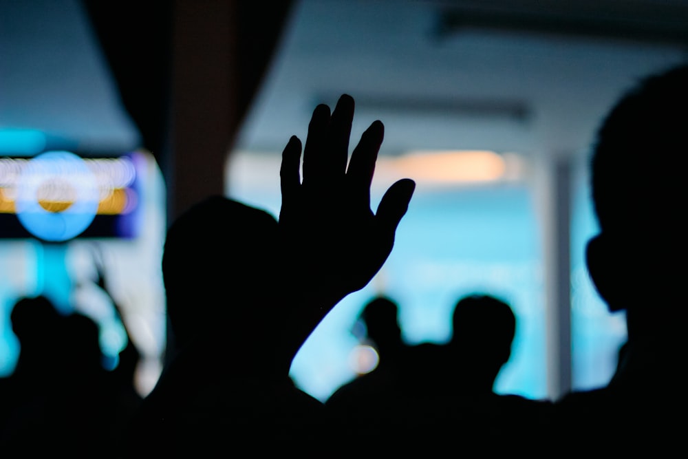 a silhouette of a person holding their hands up in the air