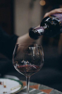 a person pouring wine into a wine glass