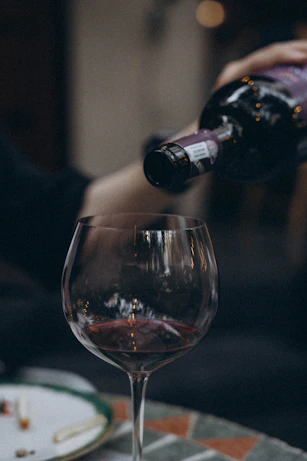 a person pouring wine into a wine glass