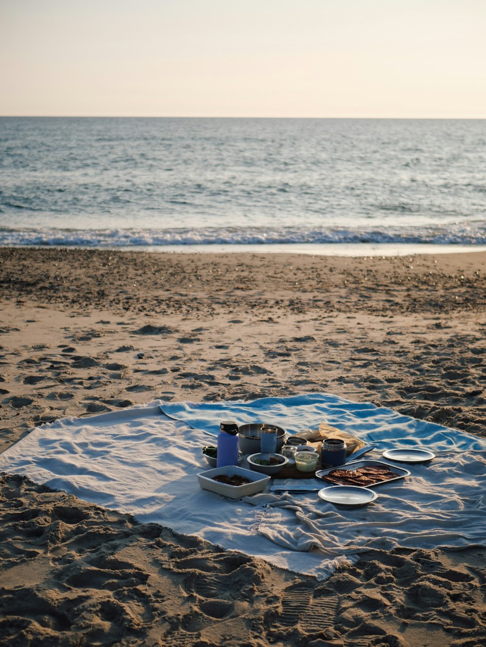 a blanket on the beach with food on it