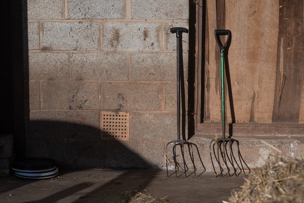 a set of garden tools sitting next to a brick wall