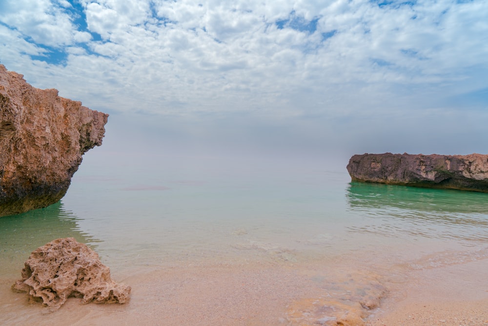 a rocky outcropping on a beach with clear water