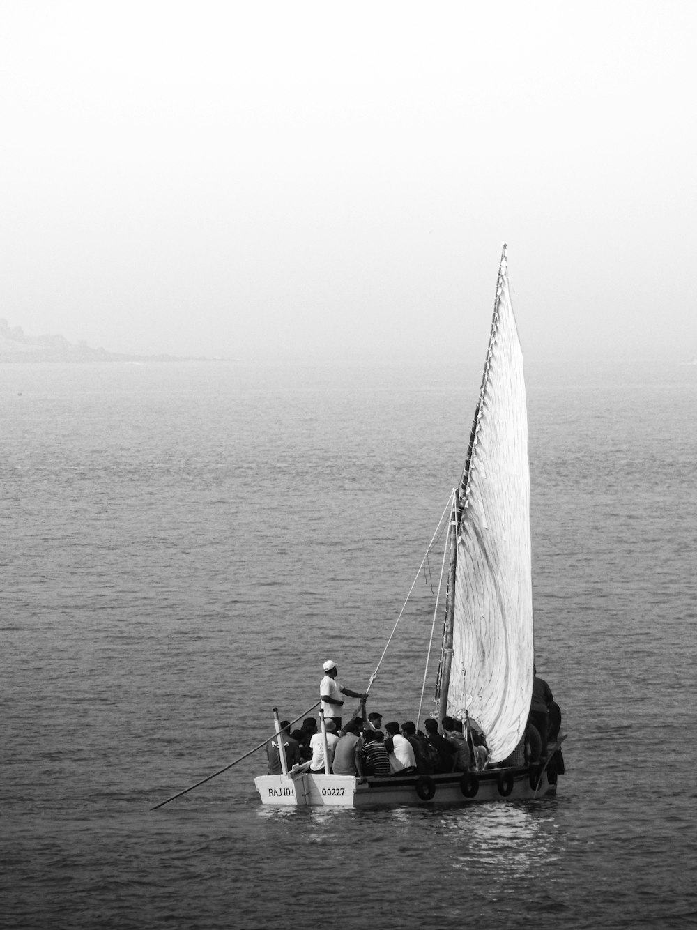 a black and white photo of a sailboat in the ocean