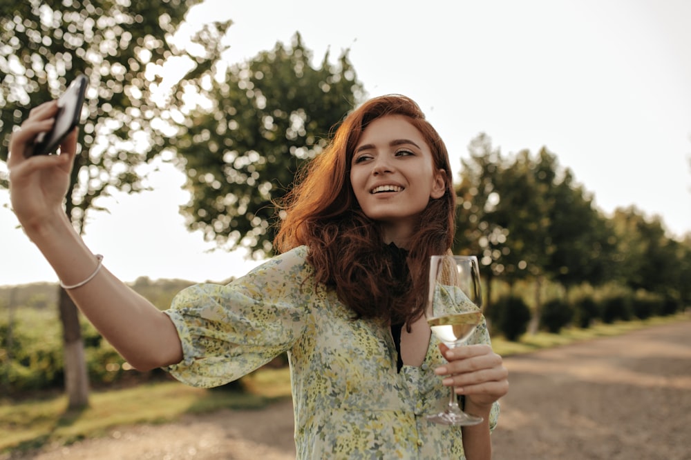 a woman holding a glass of wine and a cell phone