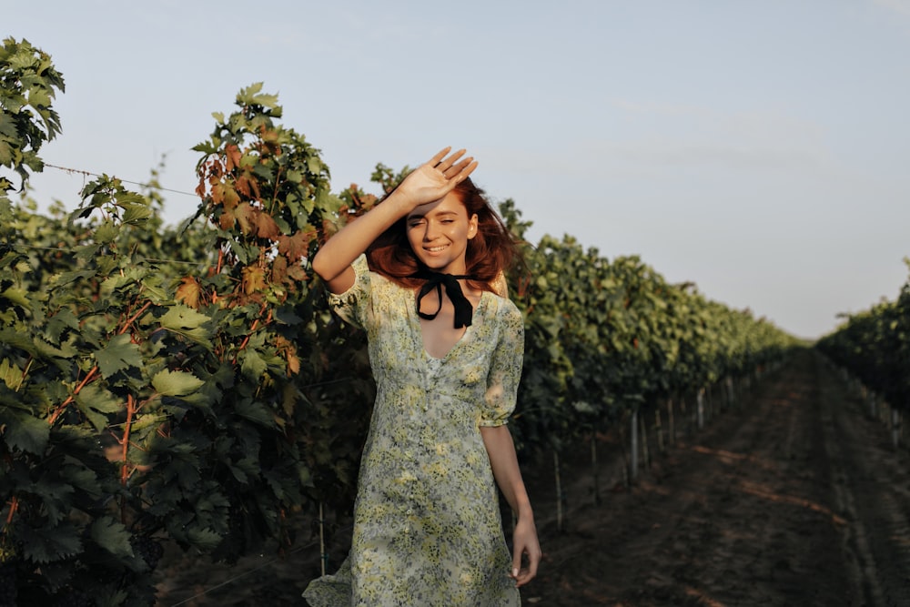 a woman standing in a field with her hands on her head