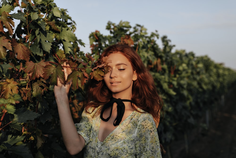a woman standing in a vineyard holding a bunch of grapes