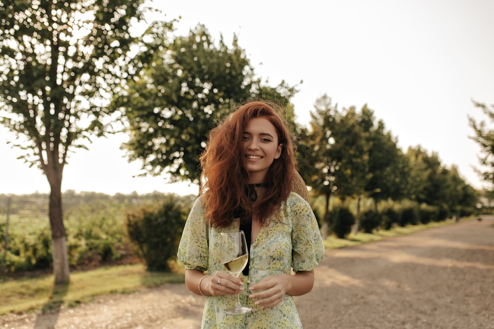 a woman standing on a road holding a glass of wine