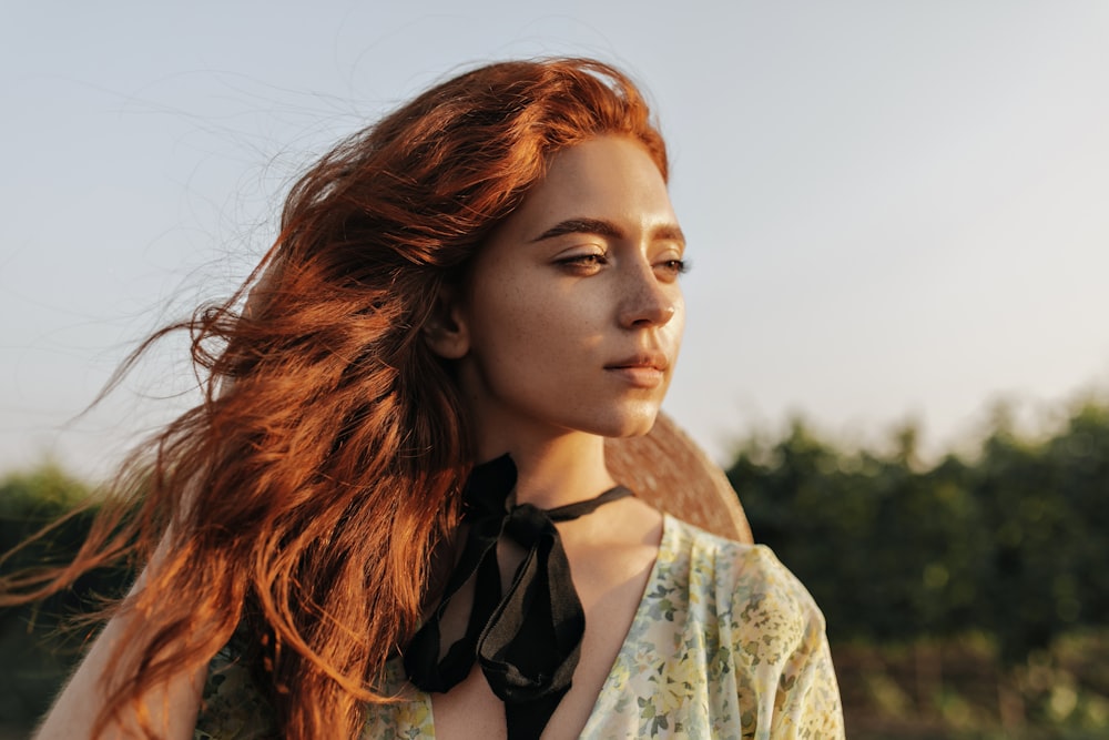 a woman with long red hair wearing a black tie